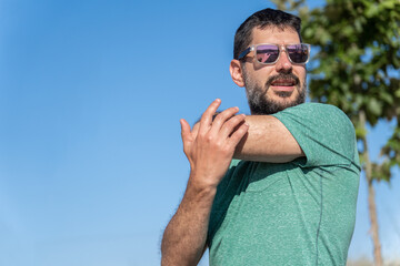 man with beard and sunglasses stretching his shoulders