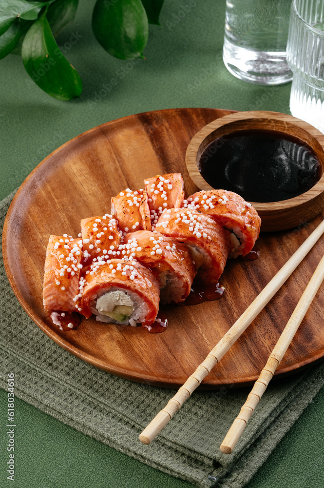 Wall mural asian sushi rolls on a wooden plate and a green background