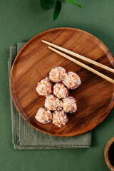 asian sushi rolls with cheese caps on a wooden plate