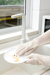 A woman wears rubber gloves to clean things in the kitchen,,Performance testing of rubber gloves, brochure image, indoor shot, close-up