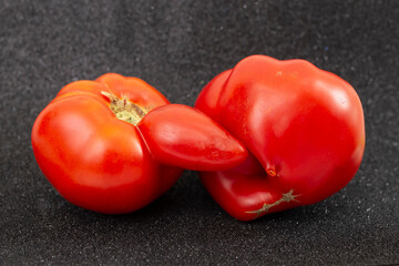 Two unusual shaped tomatoes, on black glitter background,