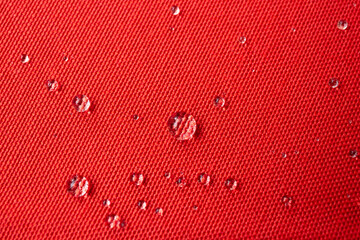 Clear water drops on red canvas,