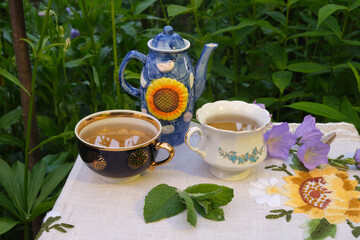 mint tea outdoors in mugs, a sugar bowl, flowers