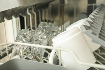 Open dishwasher with metal shelves for dishes