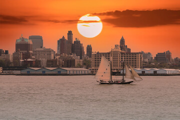 Cityscape with sailboat on the river and beautiful sunset sky