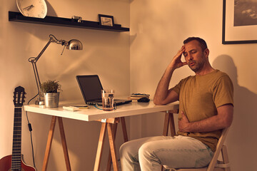 Fototapeta na wymiar Man with stomach pain and headache while working at home on a laptop.