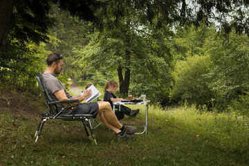 Father and daughter enjoying some family time together in nature painting and drawing - 618052490