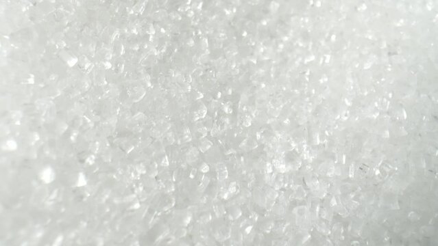 The camera moves closer, the surface of the sugar crystals becomes more apparent. It reveals a fine layer of irregular, shallow indentations and facets, giving the crystals a unique texture. 4K HDR
