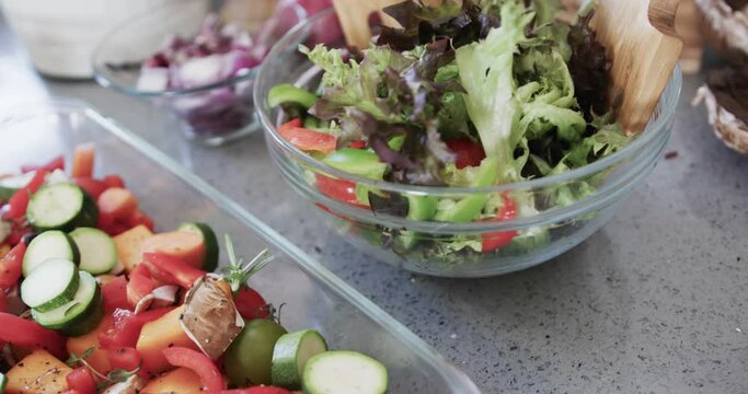 Close up of chopped vegetables and salad on worktop in kitchen, slow motion
