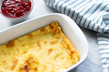 Pie in the baking dish. Strawberry jam in a bowl. Striped napkin. Top view.