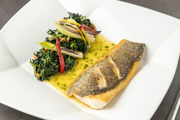 Grilled sea bass fillet served with garnishes in a fine dining restaurant