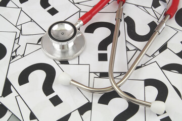 Health care and medical FAQ concept. Red stethoscope on question marks background.