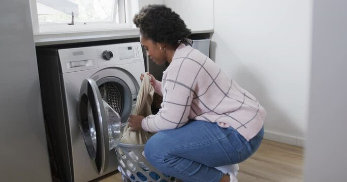 African American Woman Putting Clothes Into Washing Machine, Doing Laundry At Home, Slow Motion