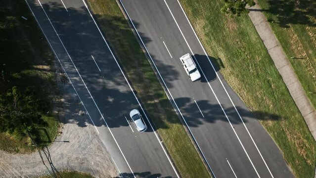 Rotating drone footage of traffic cars on asphalt road with grass in the afternoon