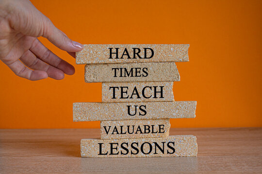 Lesson from hard times symbol. Concept words Hard times teach us valuable lessons on brick blocks on a beautiful orange background. Businessman hand. Business lesson from hard times concept.