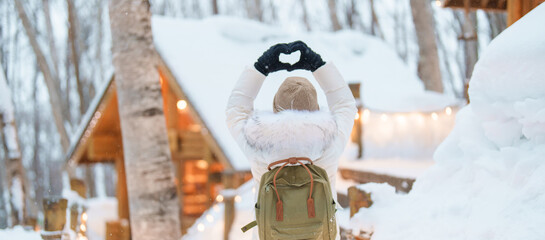 Woman tourist Visiting in Furano, Traveler in Sweater sightseeing Ningle Terrace Cottages with Snow...