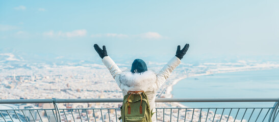 Woman tourist Visiting in Hakodate, Traveler in Sweater sightseeing view from Hakodate mountain with Snow in winter. landmark and popular for attractions in Hokkaido, Japan.Travel and Vacation concept - obrazy, fototapety, plakaty