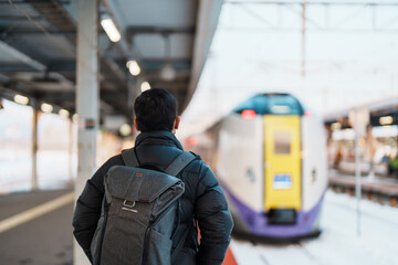 man tourist with bag in Train Station platform with Snow in winter. Hakodate, Hokkaido,...