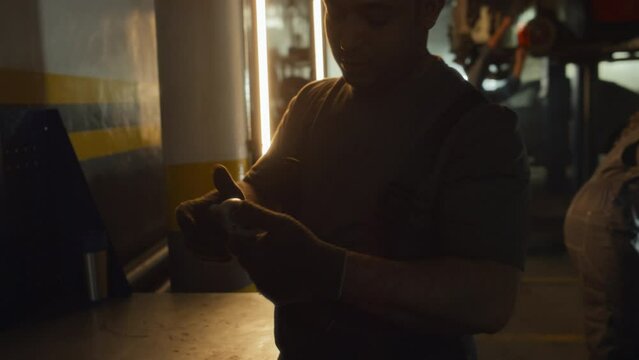 Middle Eastern man working in car service garage adjusting wrench hand tool then helping his female co-worker to fix part of engine