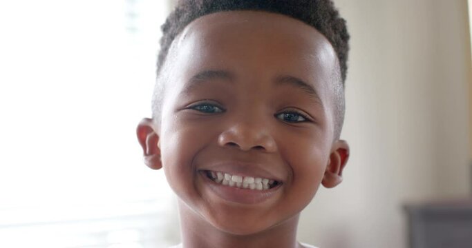 Portrait of happy african american boy looking at camera and smiling in slow motion