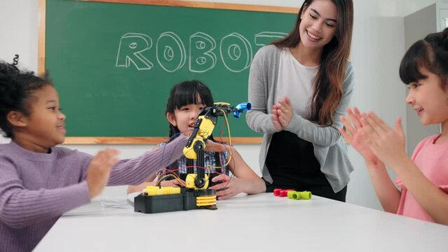 Smart primary students grouping to learning robot free electives with female teacher in classroom. Caucasian teacher female teach children assemble robot in science subject at elementary school.