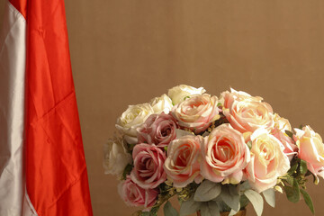 Front cover of pink plastic flower bouquet with Indonesian red and white flag isolated on brown background