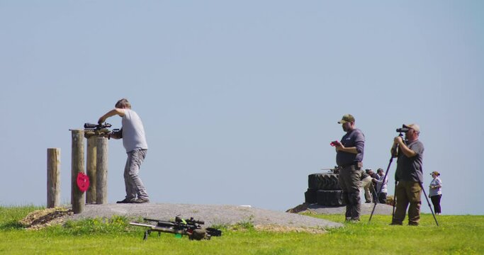 Sharpshooter Aiming At Range With Another Man Looking Through Binoculars At Precision Rifle Competition In Leach, Oklahoma. wide