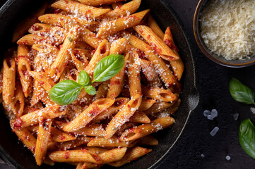 Penne Pasta with tomato sauce, parmesan and fresh basil in a pan. Top view,