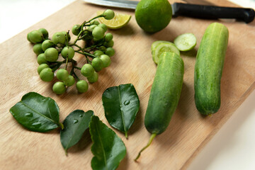 Group or various of Healthy diet raw food ingredients Thai pea eggplant or Turkey berry, kaffir lime leaf, cucumber and lime on bamboo wooden chopping board Healthcare good lifestyle concept 