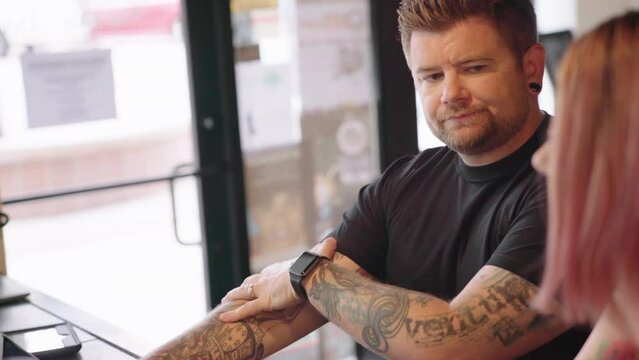 Professional Tattoo Artist explaining the process for a female customer in a tattoo salon