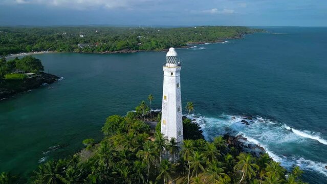 Aerial video of Dondra Lighthouse surrounded by tropical trees and the sea, Sri Lanka