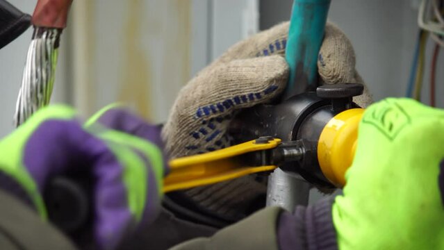 Close-up view of Electrician installing wires, cables into a electricity power shield, fuse box, an industrial electric panel with lots of colorful cables and wires. Power industry concept.