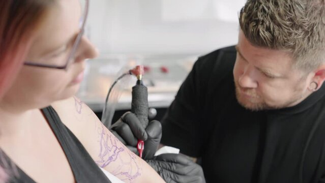 Professional Tattoo Artist drawing and outlining a tattoo on a red hair female arm
