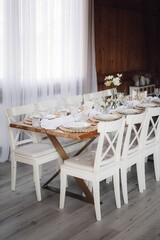 Interior of restaurant with wedding table and white chairs adorned with flowers
