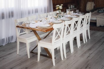 Interior of restaurant with wedding table and white chairs adorned with flowers