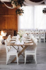Interior of restaurant with wedding table and white chairs adorned with flowers