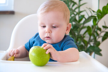 baby eating apple sitting in a high chair