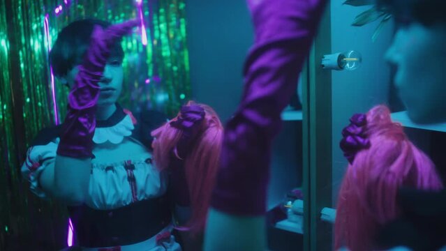 Gen Z girl cosplaying anime character standing in front of mirror taking off her wig then fixing her own hair