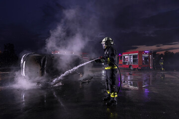 Fototapeta premium Firefighters fight the fire flame to control fire not to spreading out. Firefighter industrial and public safety concept. Traffic or car accident rescue and help action. 
