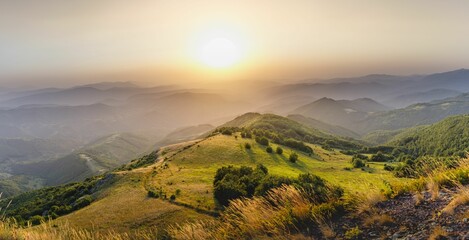 Fototapeta na wymiar Scenic landscape of rolling hills covered in lush green grass at sunset.