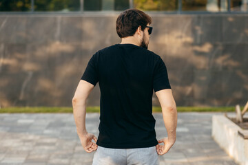 Young stylish bearded man  in a black T-shirt and sunglasses. Street photo