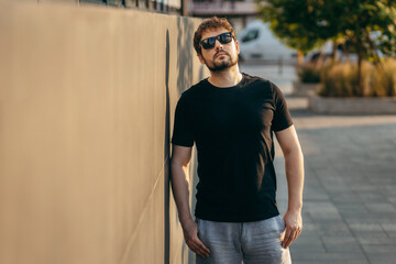 Young stylish bearded man  in a black T-shirt and sunglasses. Street photo