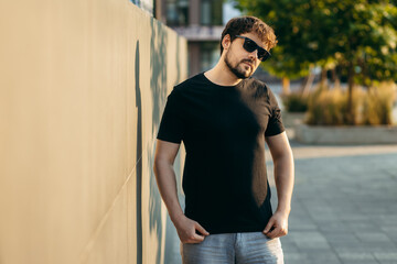 Young stylish bearded man  in a black T-shirt and sunglasses. Street photo