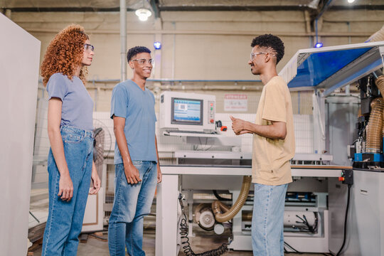 students from a Brazilian technical school paying attention to the teacher's explanation during a practical class in a factory
