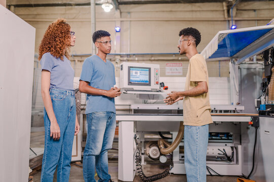 Brazilian teacher explaining to students how a machine works in a factory during a class at a technical school in Brazil