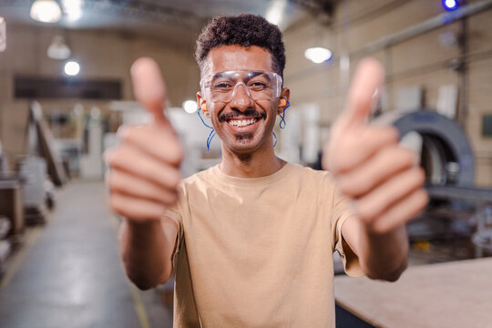 portrait of an Latin man technical course teacher wearing goggles and doing a positive sniff at the camera in an industrial setting