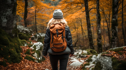 Fototapeta na wymiar A Young Woman in Hiking Gear Walking a Trail in a Beech Forest During Autumn