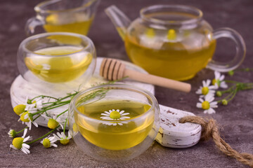 Medicinal chamomile flower tea on a gray background.
