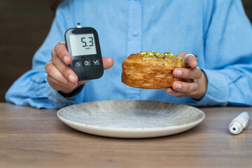 Woman showing glucose level and holding high carb food. Life with diabetes