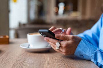 Woman using mobile phone in coffee shop at breakfast table